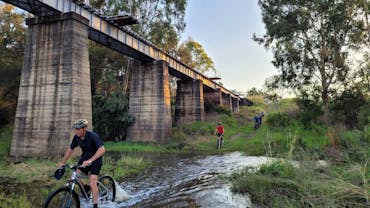 Riders going through water in the gully at the Golembil Bridge