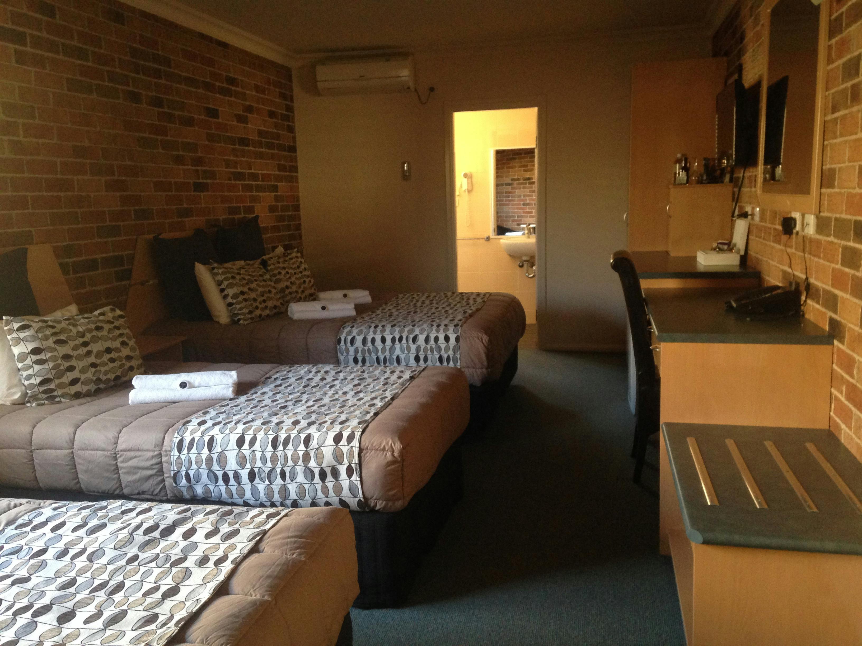 左側に3つのベッド、背景にバスルームのドア。右側に机としなやか。