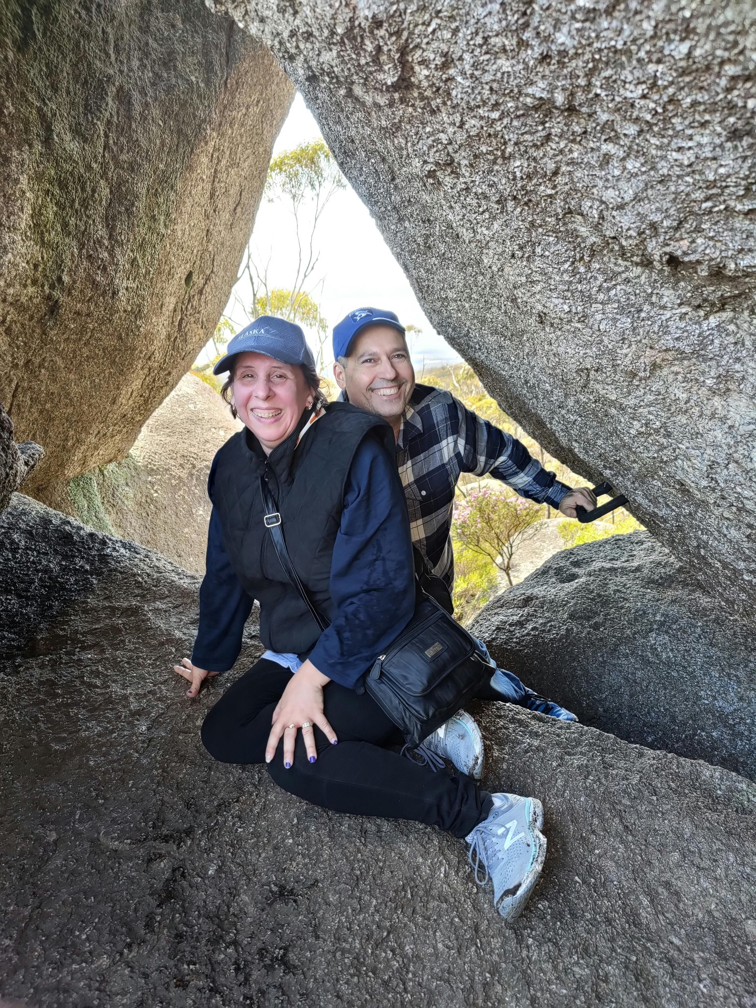 man and woman sitting together on and between large  granite rocks