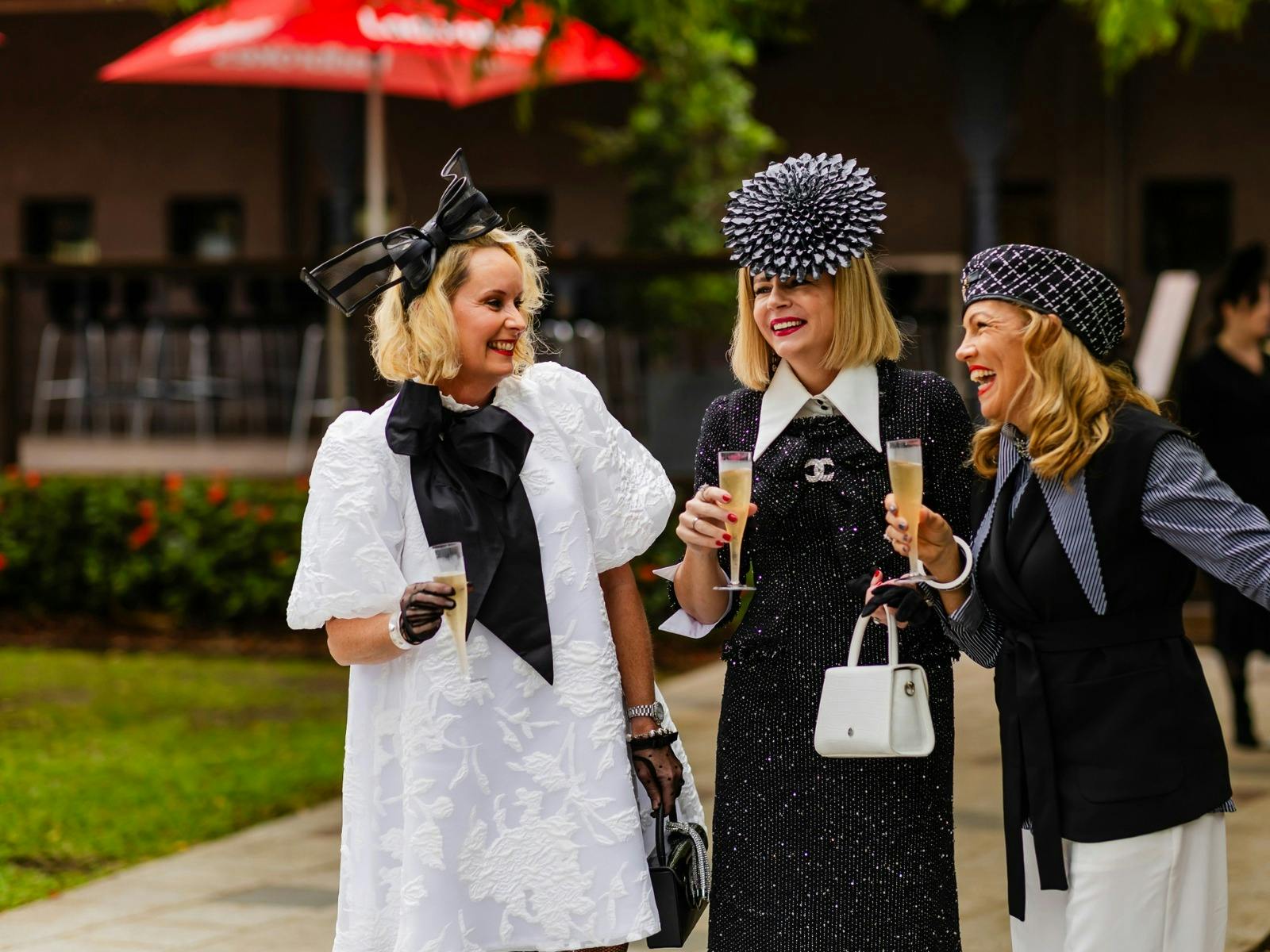 Three ladies dressed in black and white attend Brisbane Racing Club's Derby Raceday