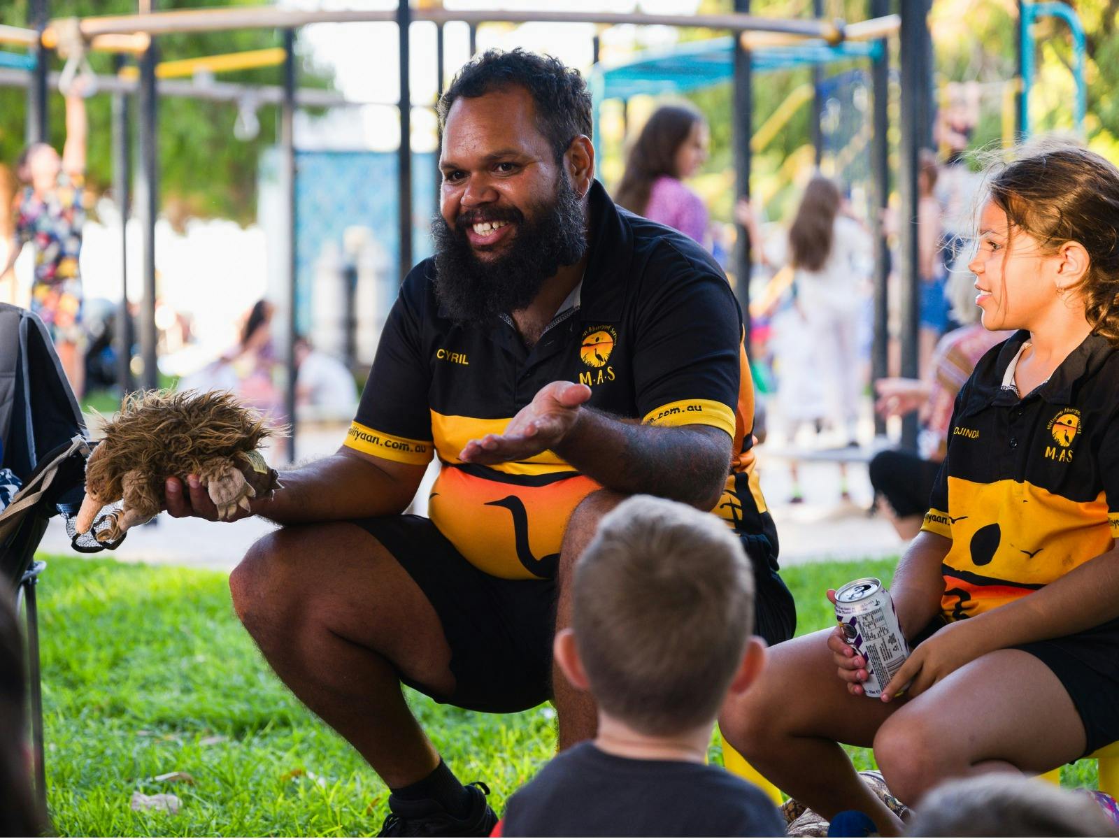 Man wearing First Nations T-shirt handling a toy echidna