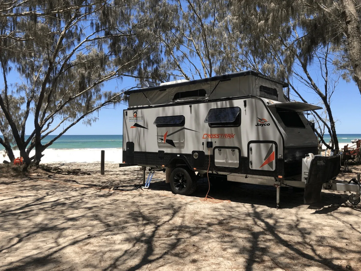 caravan parked at the beach with blue skies in the background