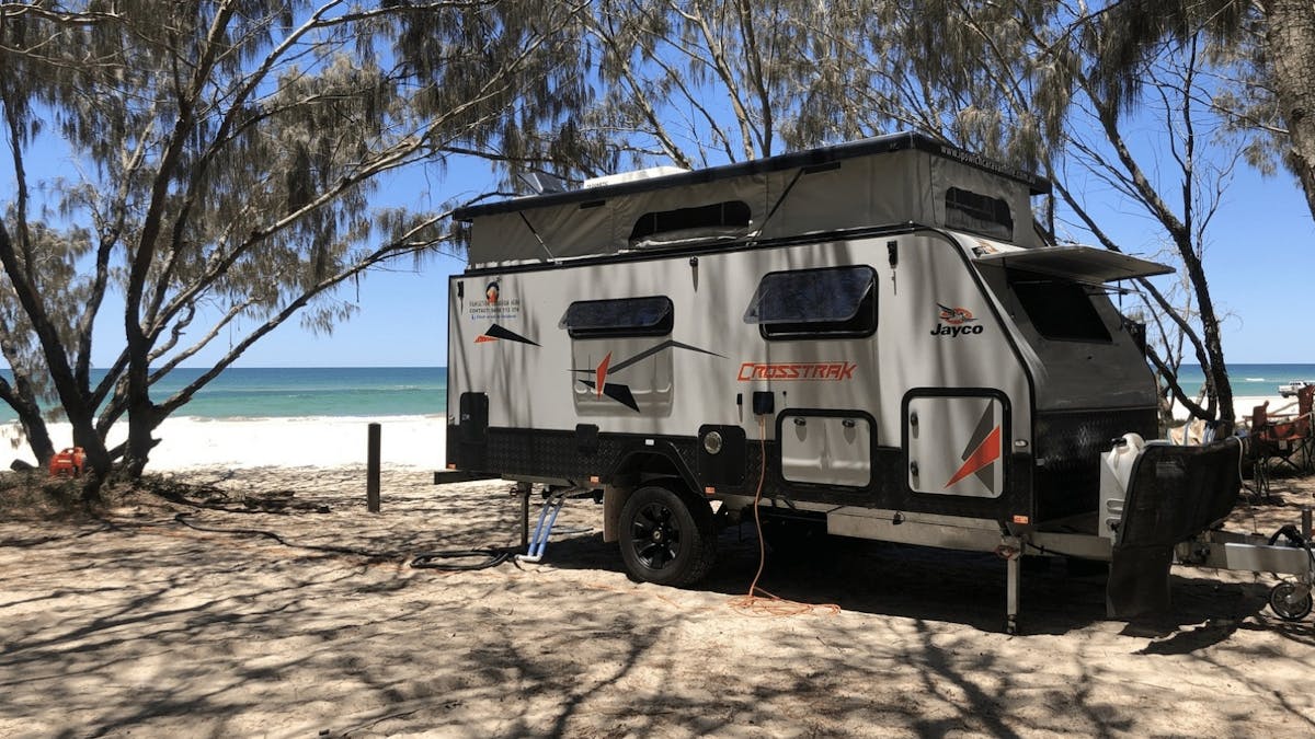 caravan parked at the beach with blue skies in the background