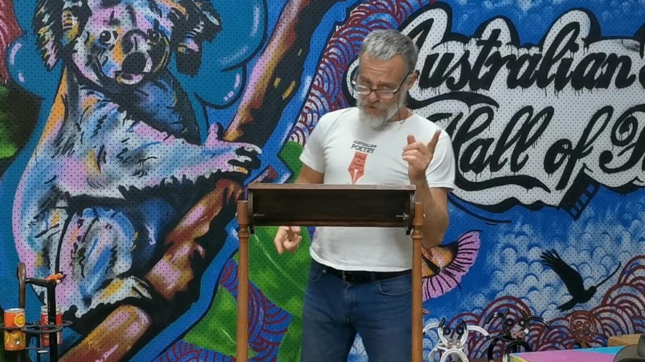 Thundercloud reciting poetry in front of Australian Poetry Hall of Fame mural