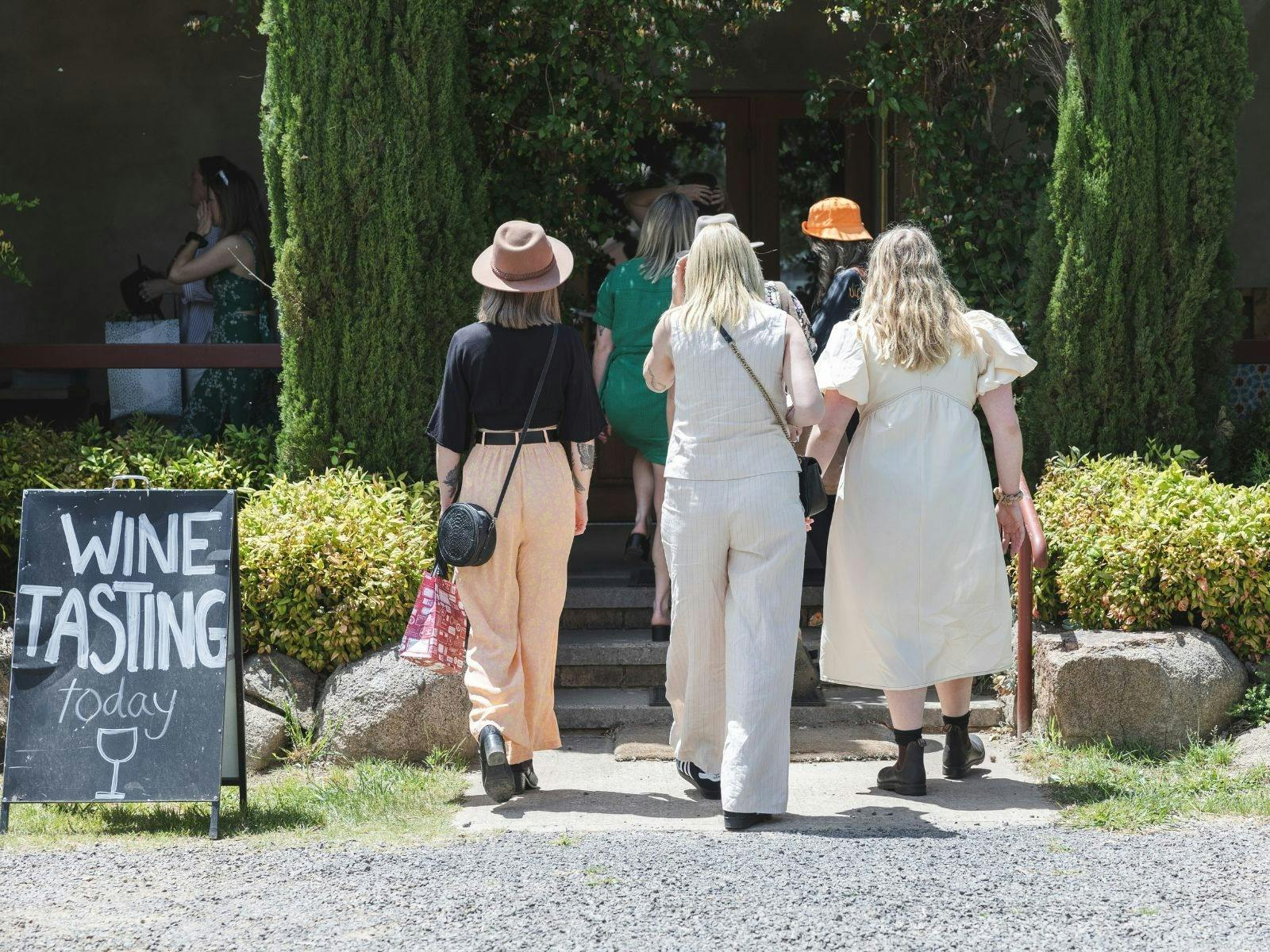 入り口にワインの試飲黒板があるワインセラーのドアに歩いていく女性たち