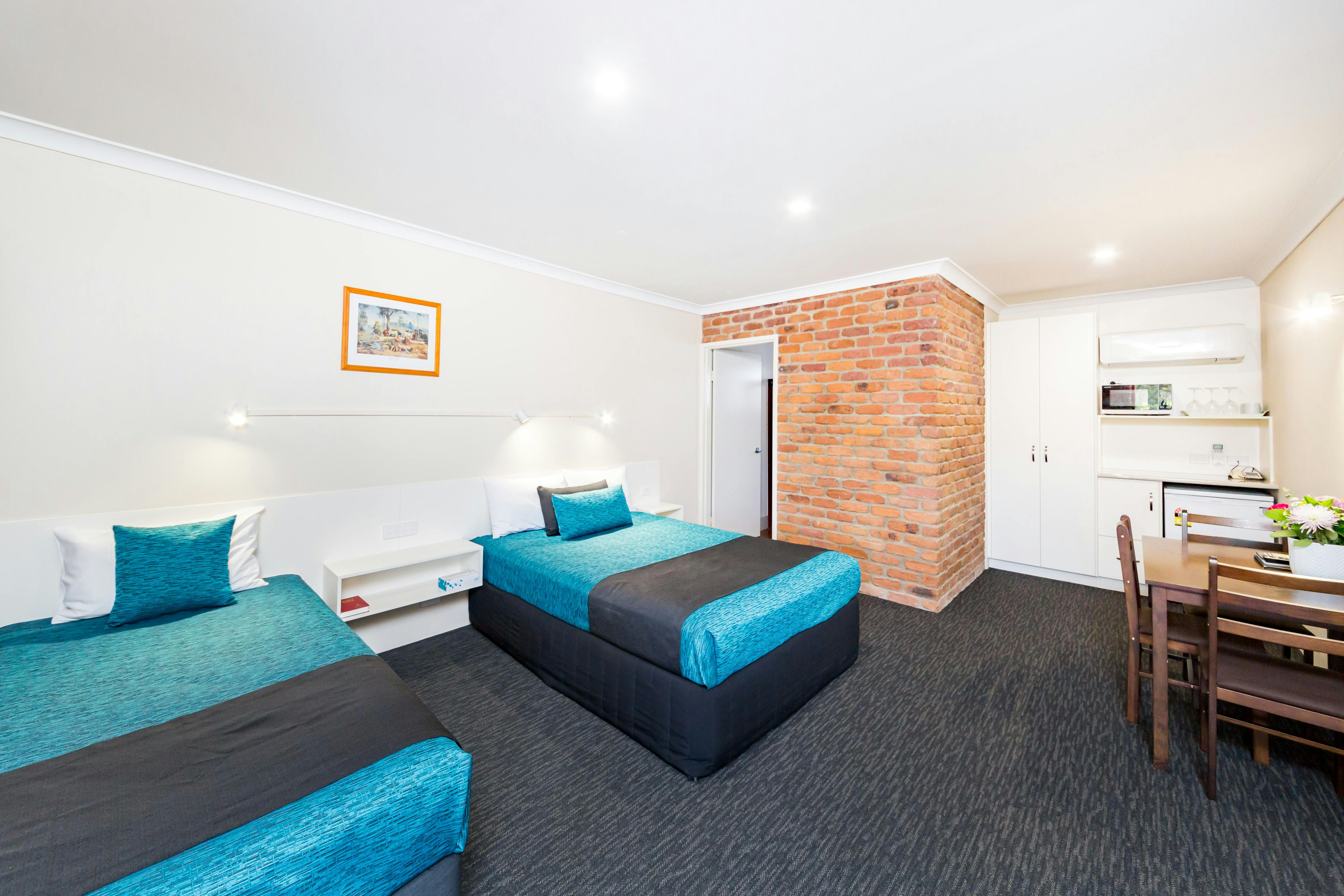 Spacious air-conditioned room with a comfortable Queen bed & Single bed, lounge, table & chairs