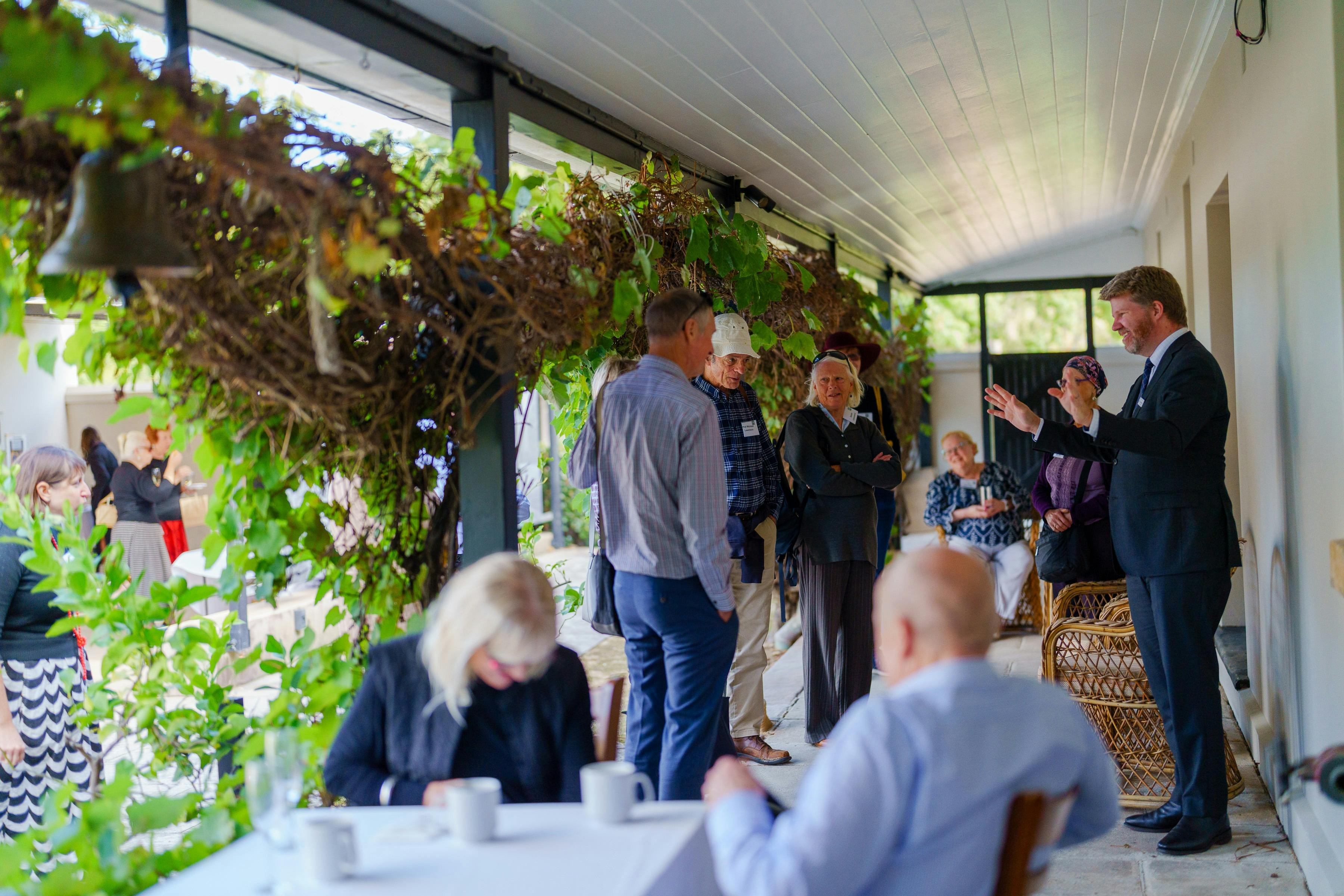 People talking under cover on verandah of historic building