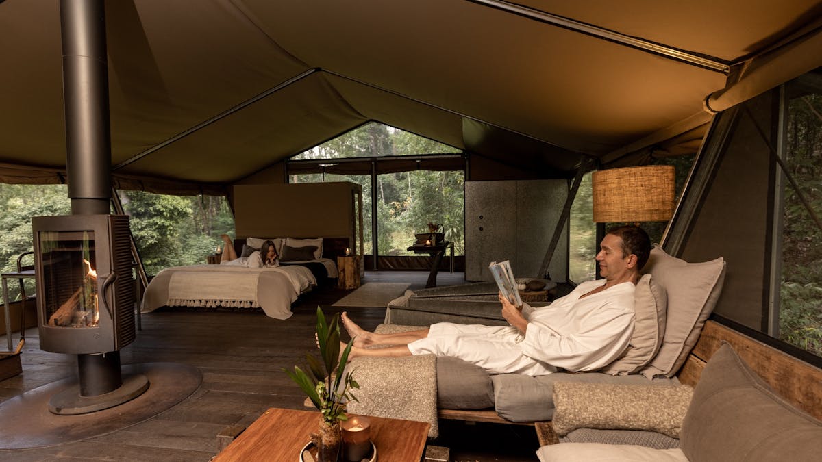 Guest couple relaxing inside safari tent accomodation.