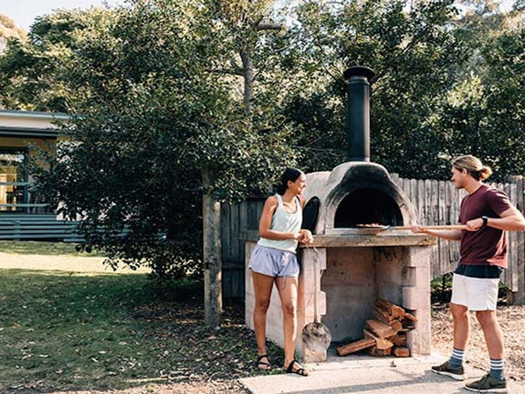 A couple use the pizza oven at Depot Beach campground, Murramarang National Park. Photo: Melissa