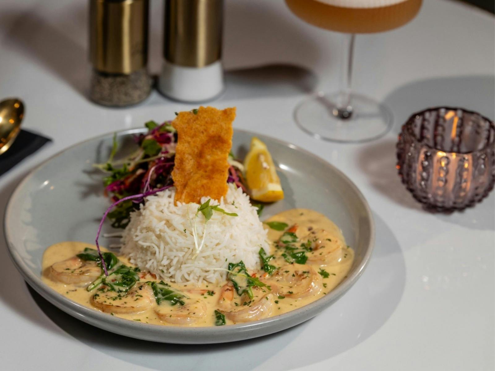 Creamy garlic prawns served with steamed rice, fresh salad, lemon and crisp garnish at The Elegance