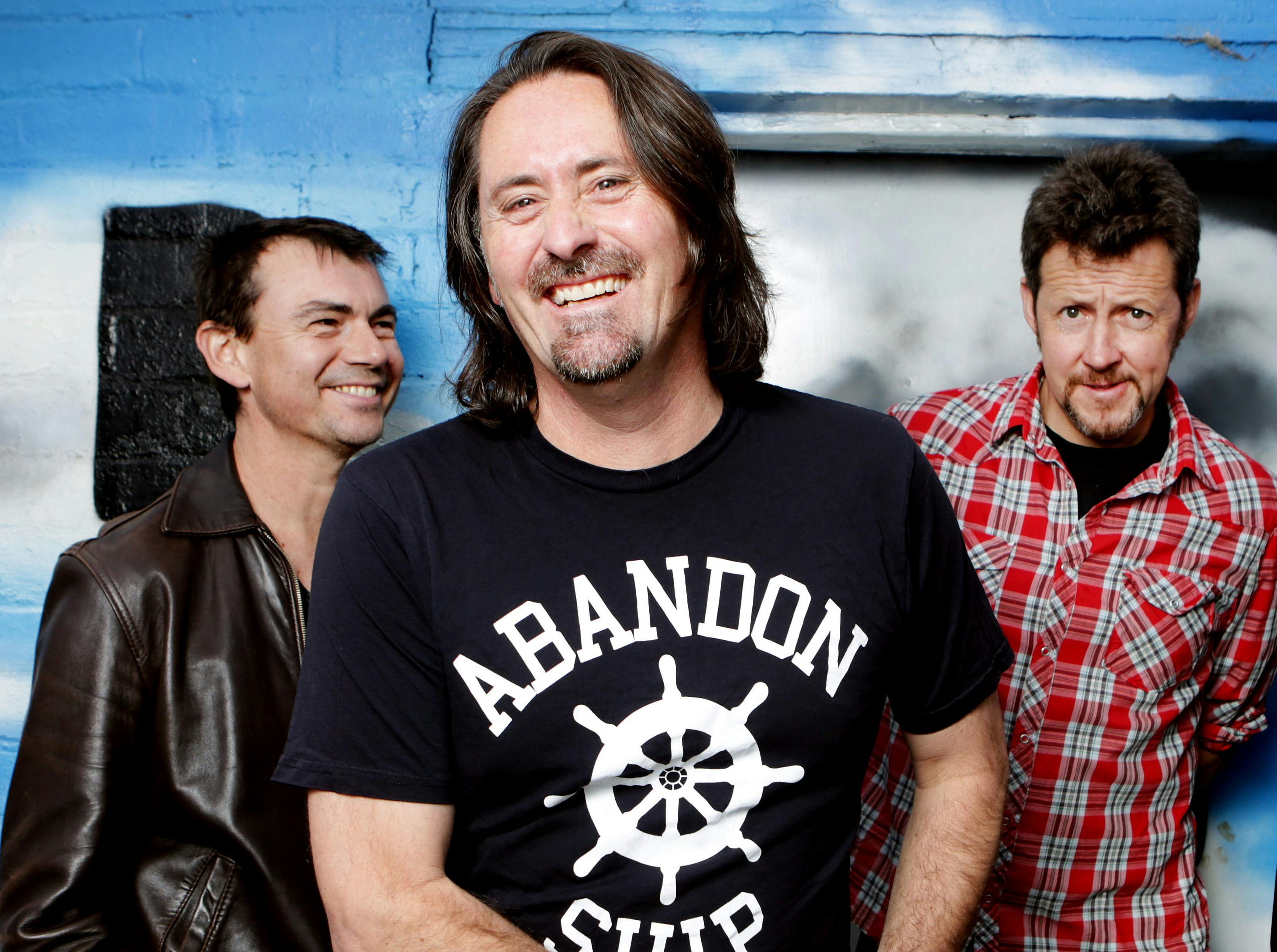 The three members of Things of Stone and Wood, casually dressed and smiling happily.