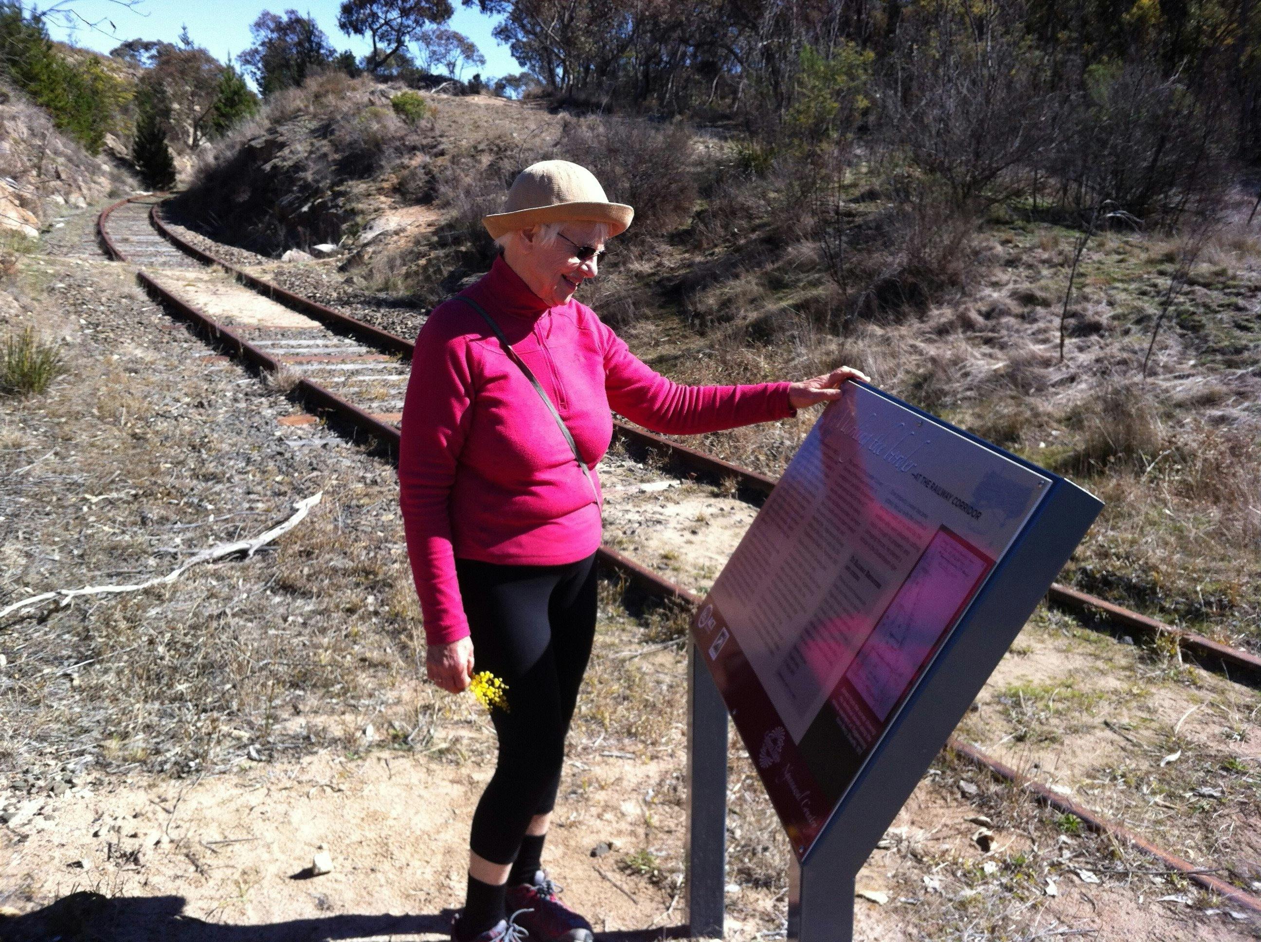 Woman reading sign board next to rail tracks