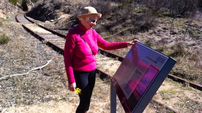 Woman reading sign board next to rail tracks