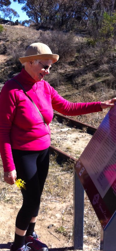 Woman reading sign board next to rail tracks