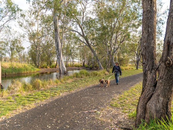A woman walking two dogs alongside the Injune Lagoon A woman walking two dogs alongside the Injune Lagoon