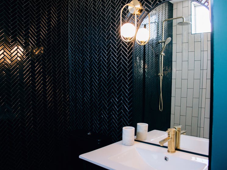 A black and white tiled bathroom with brushed gold fittings.