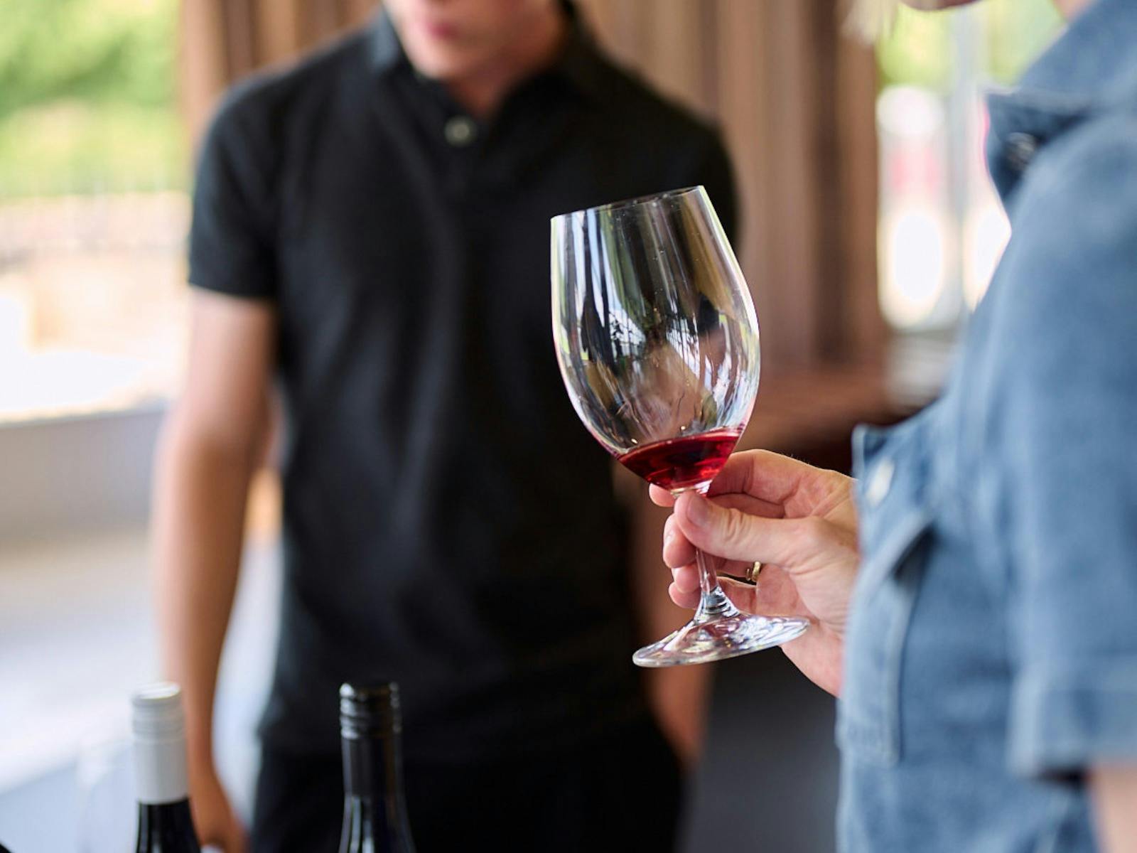 A woman holds a glass of red wine
