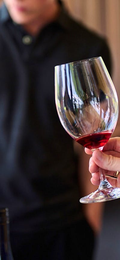 A woman holds a glass of red wine