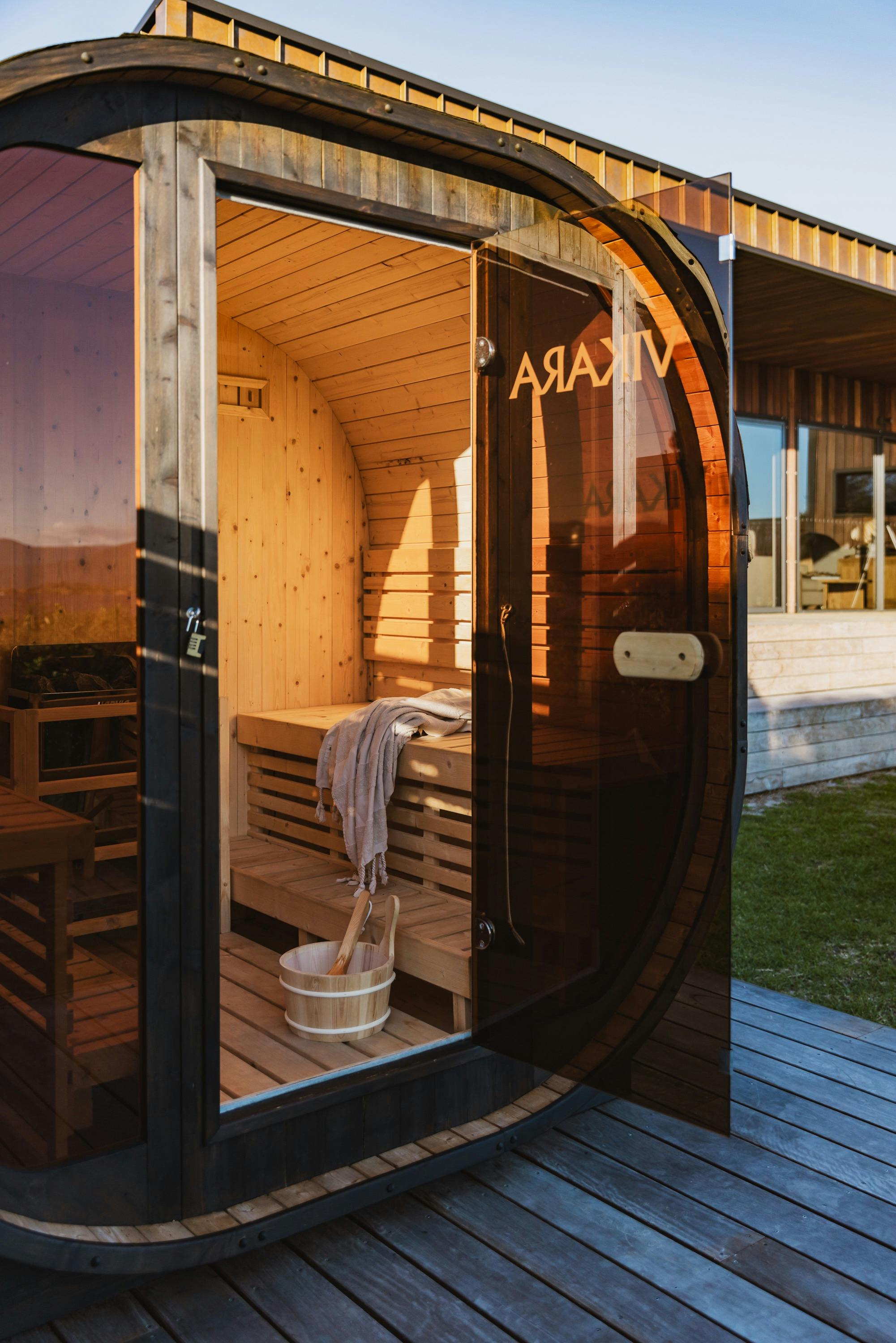 Timber barrel sauna with seating and towels, overlooking the coast at Cooinda On The Beach.