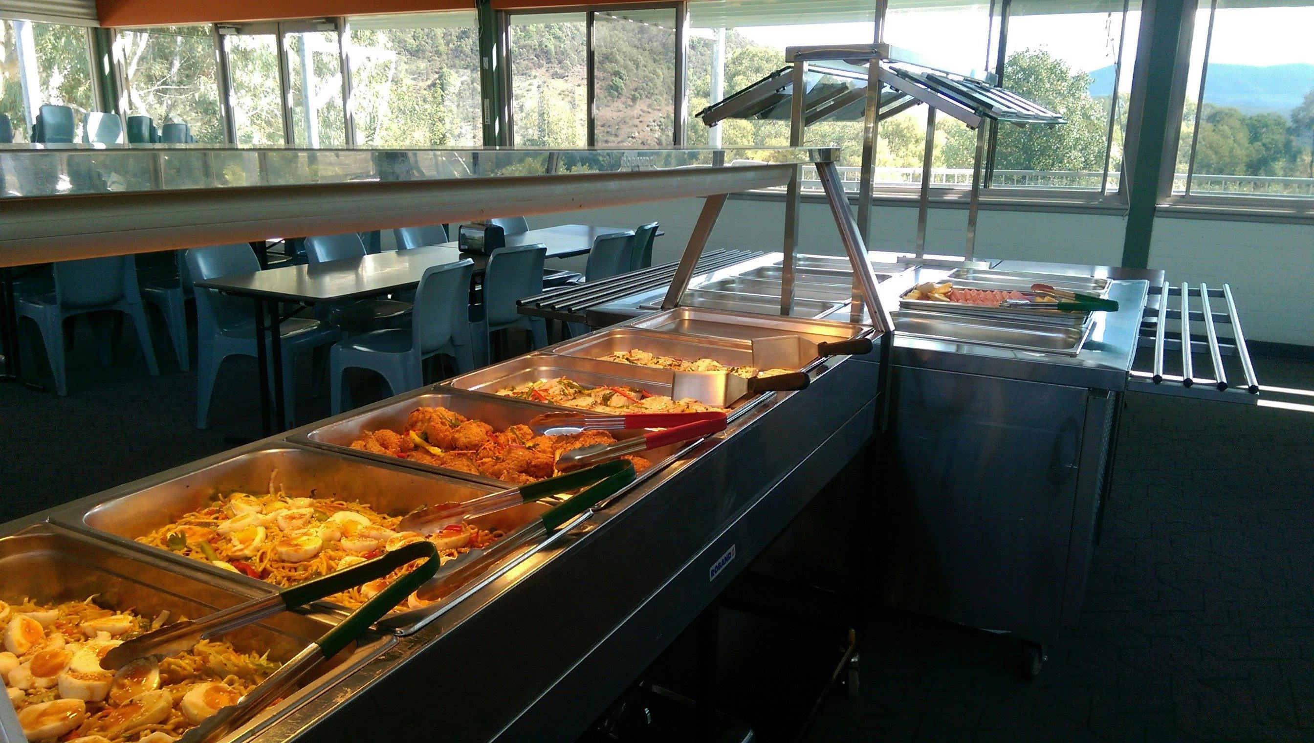trays with meals such as noodles, pieces of chicken, potato, and fruit salad