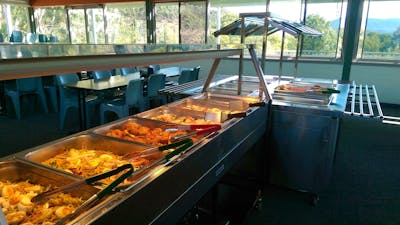 trays with meals such as noodles, pieces of chicken, potato, and fruit salad