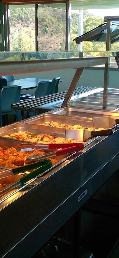 trays with meals such as noodles, pieces of chicken, potato, and fruit salad