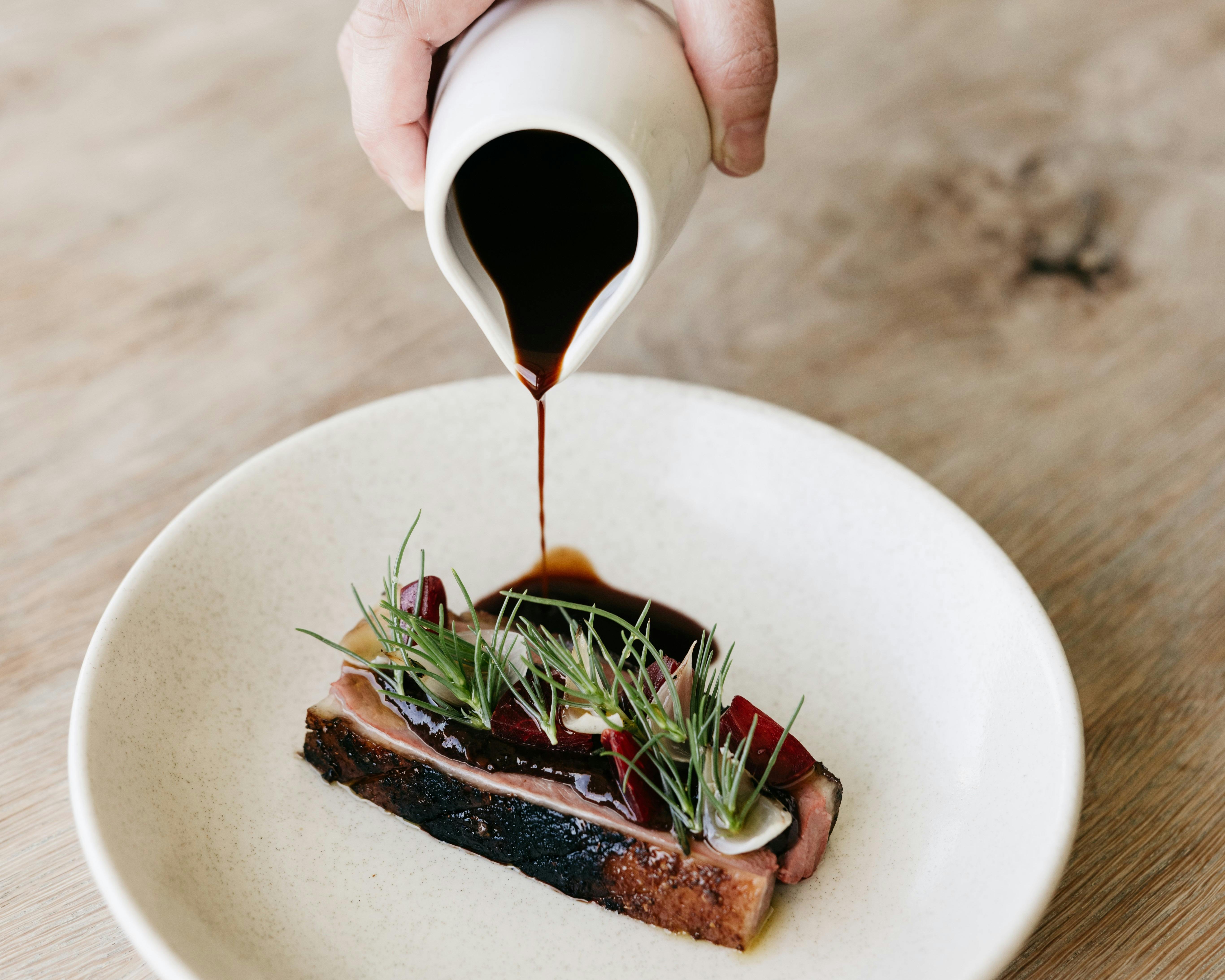 A dark sauce is poured over a dish of venison at Oakridge Restaurant