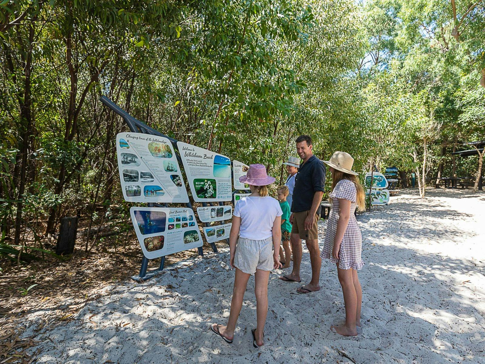 A family reading a sign on a bushwalk
