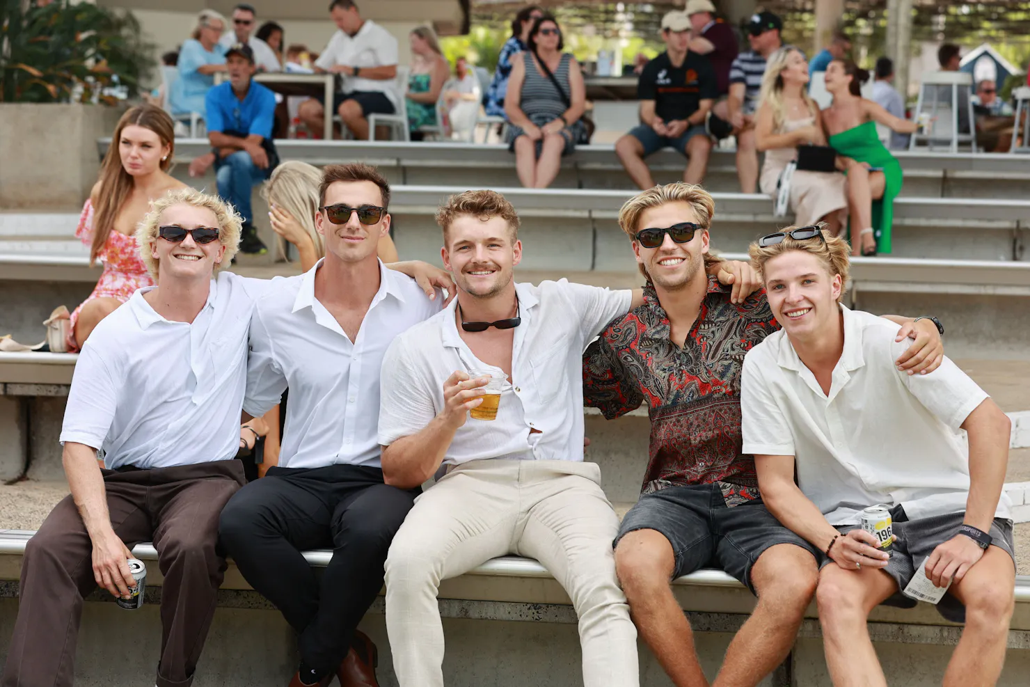 Group of mates sitting on the grandstand seating smiling at the camera