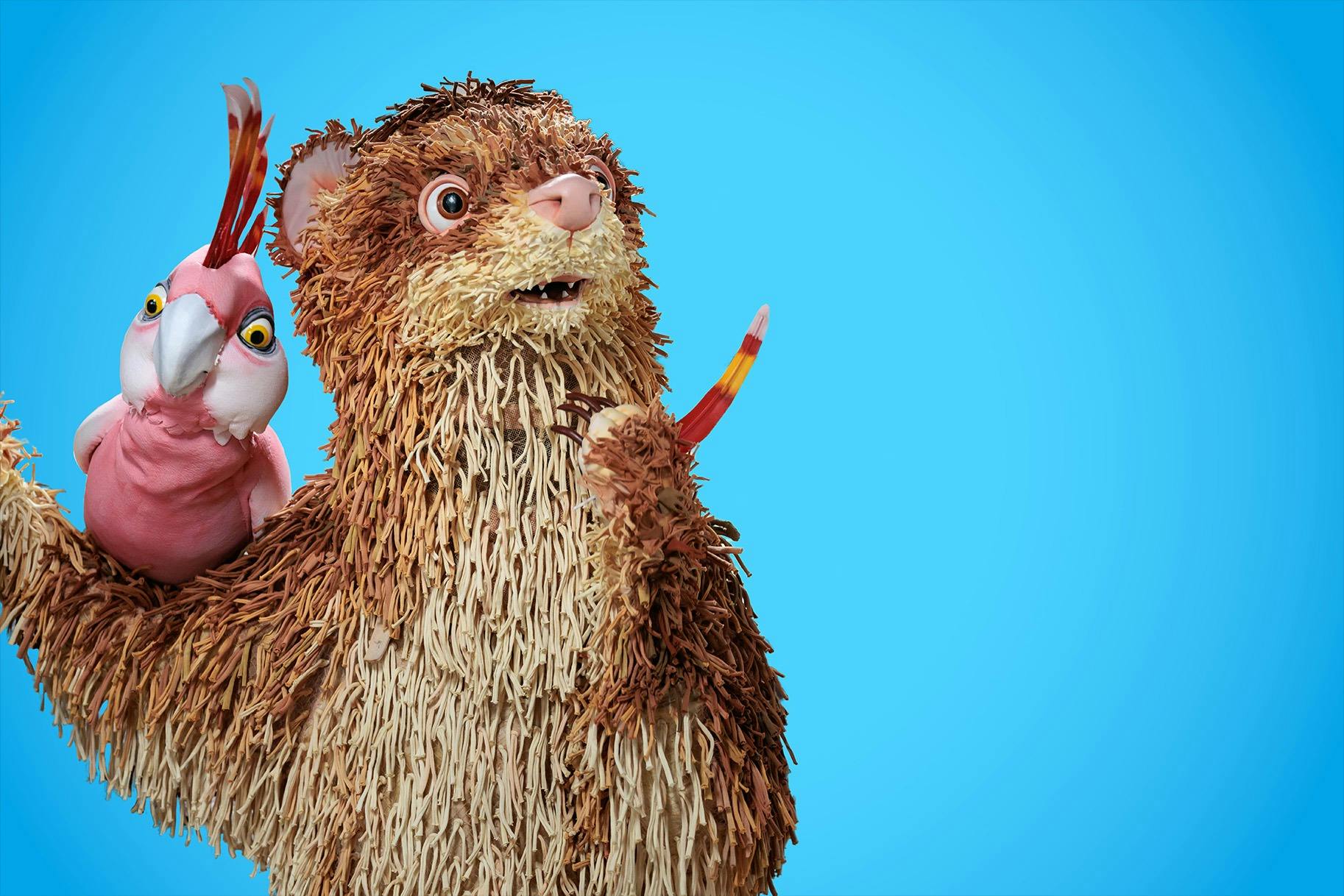 A human sized puppet ferrat with a puppet galah on it's arm