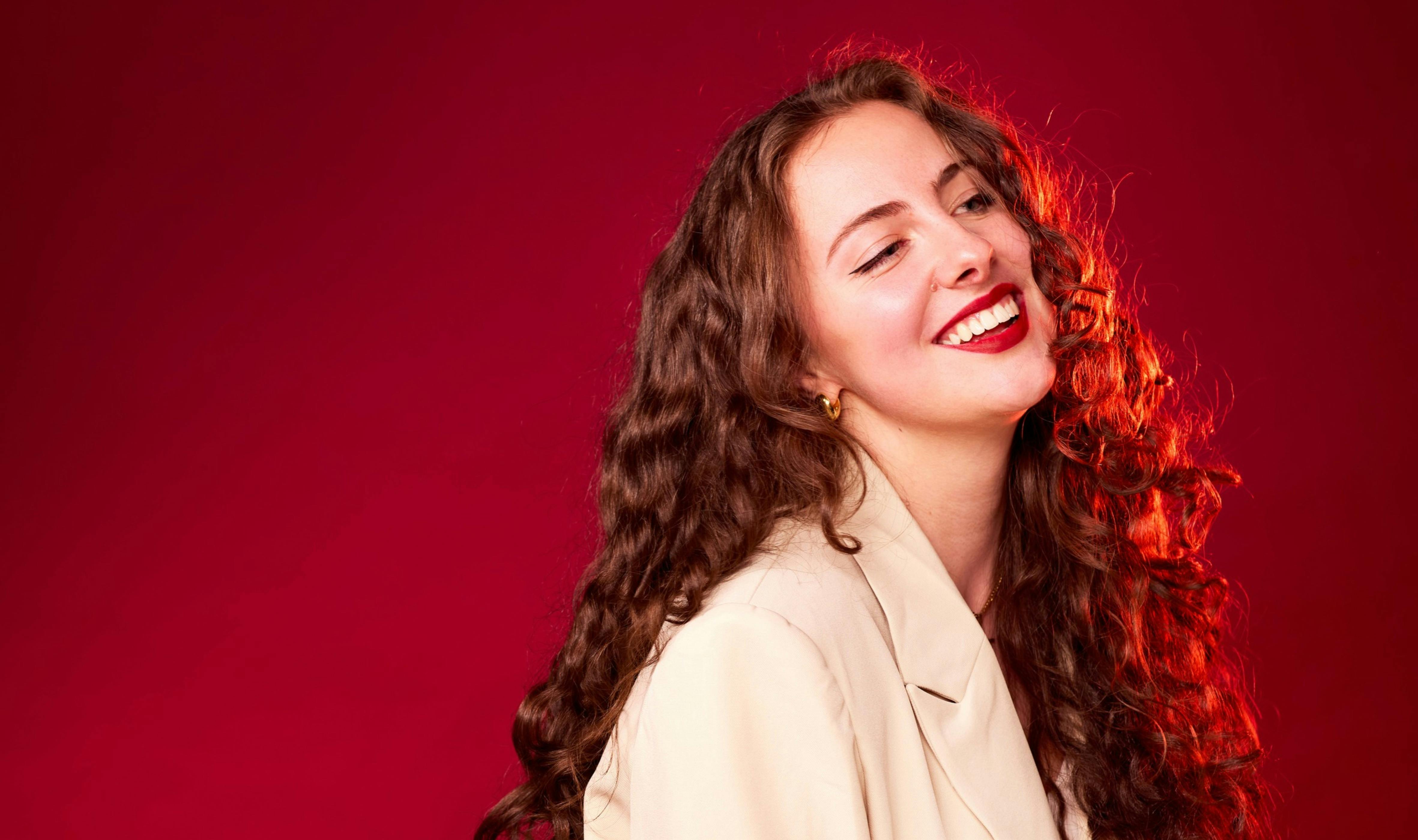 Josephine Brereton - Soprano smiles on top of a Christmas red background