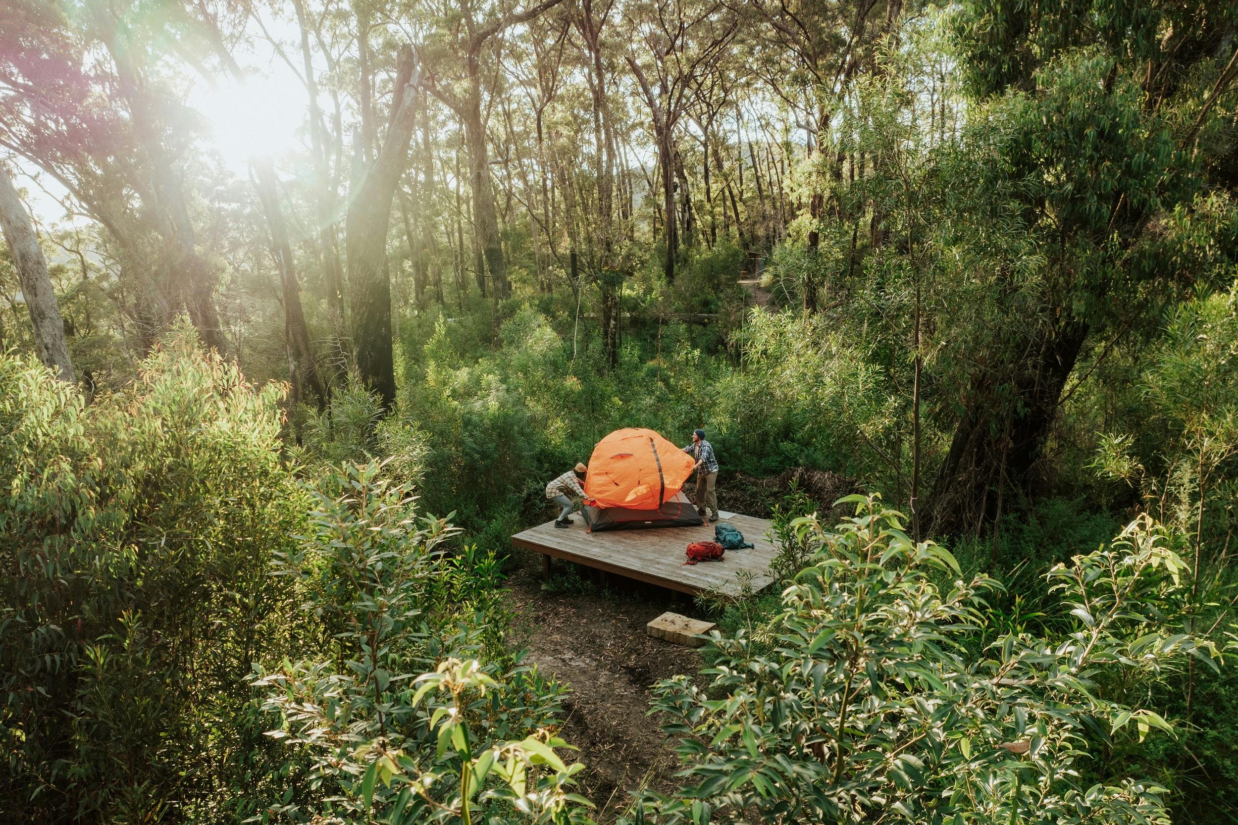 Two hikers setting up a tent on a camping platform at Sand Ridge campground.