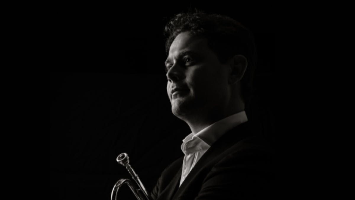 Black-and-white portrait of a trumpet player in profile, looking toward the light