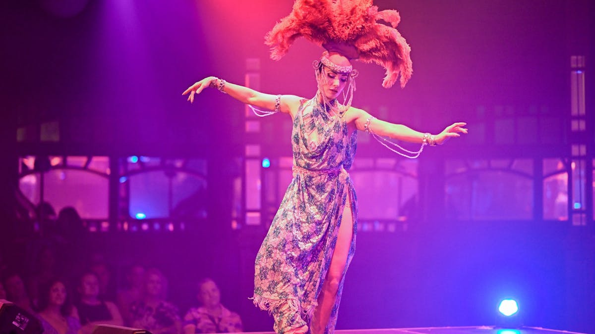 A showgirl performing onstage as a crowd watches on.