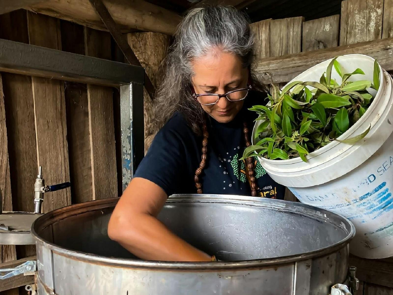 Lady pouring leaves as part of a distillation