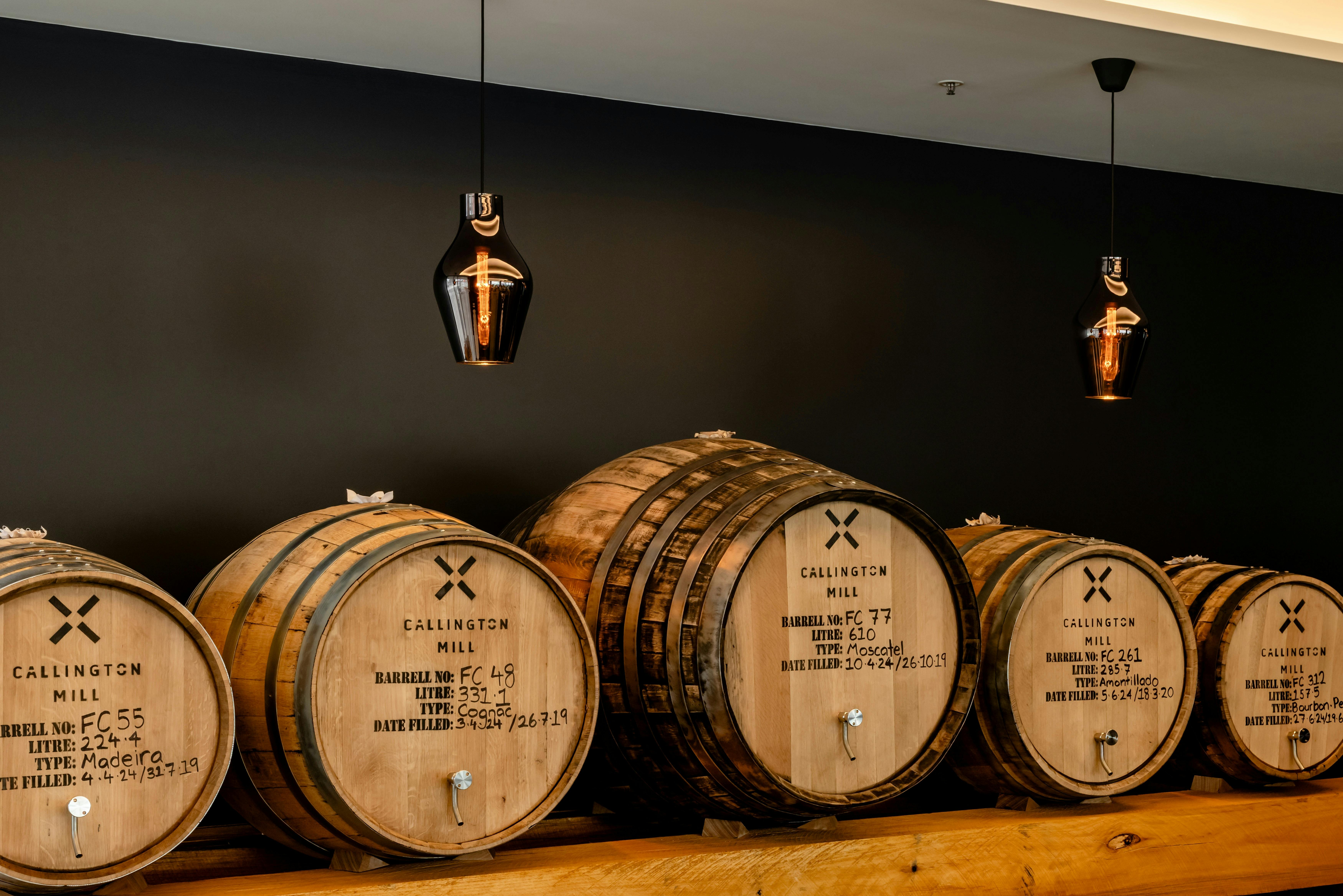 Five whisky casks of varying size lined up on a bench