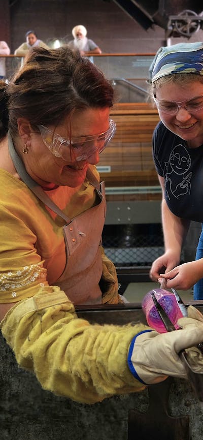 teacher and participant blowing glass in the Hotshop