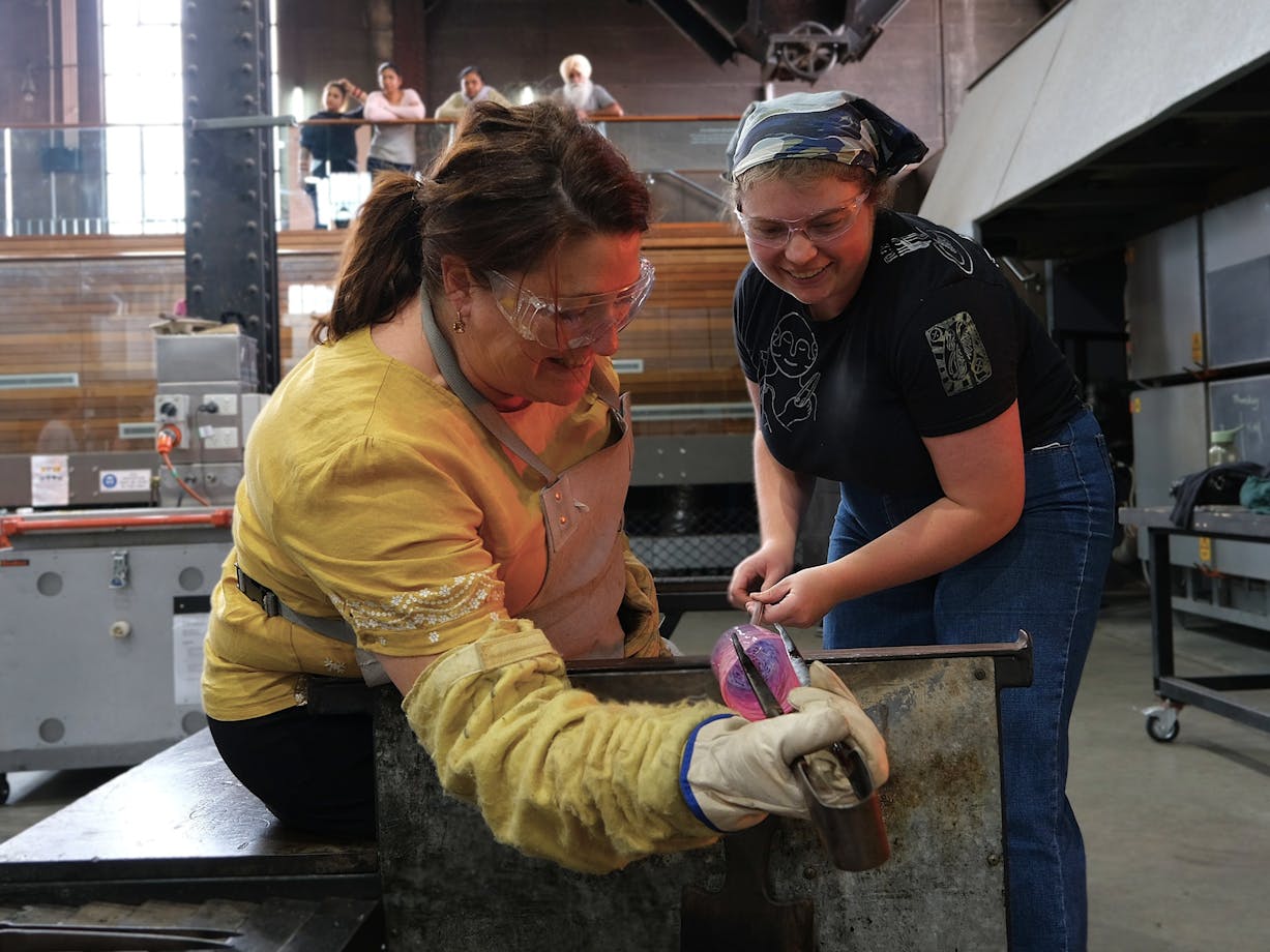 teacher and participant blowing glass in the Hotshop