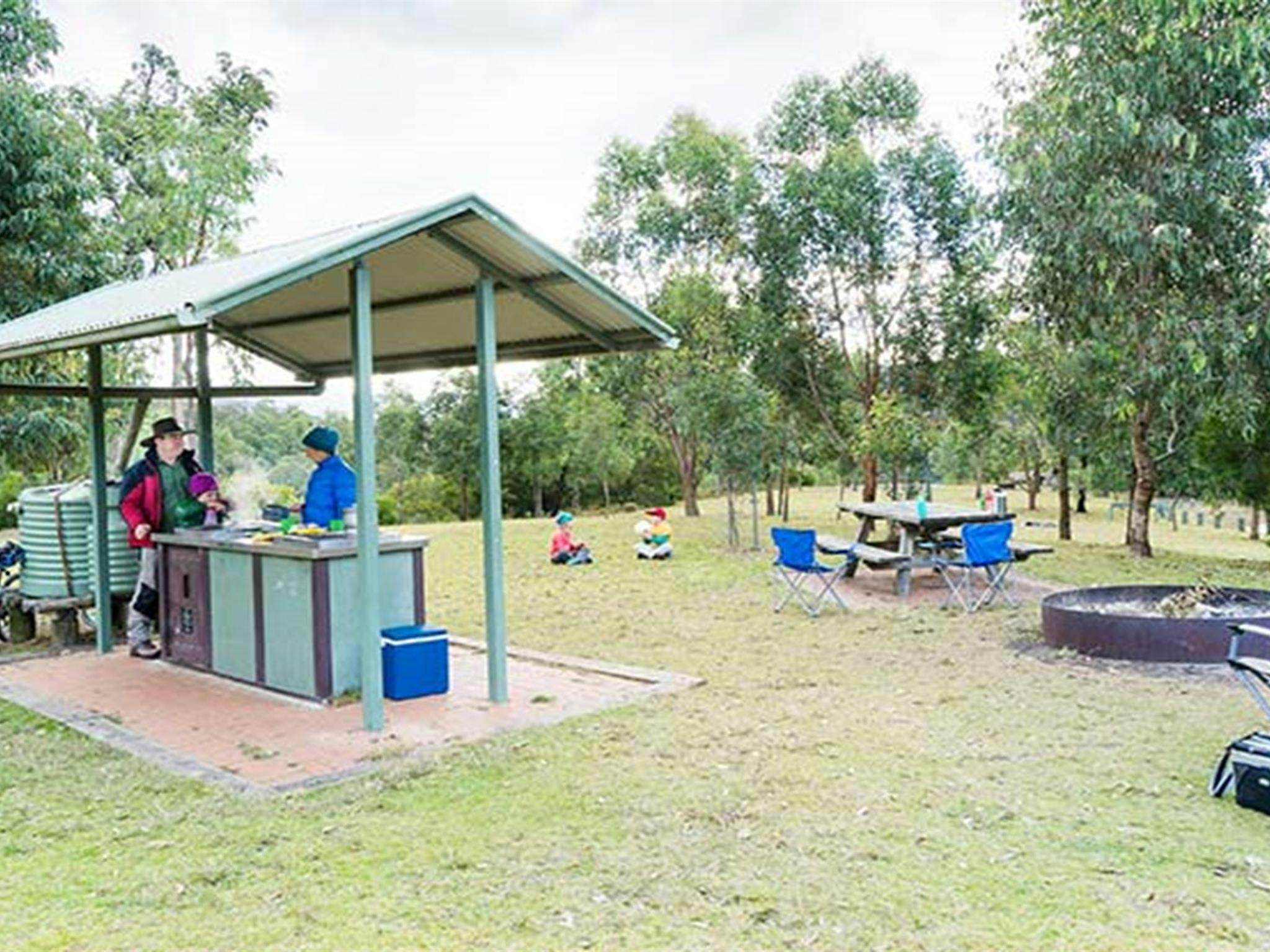 A family cooks on undercover gas barbecues at Dunphys campground, Blue Mountains National Park.
