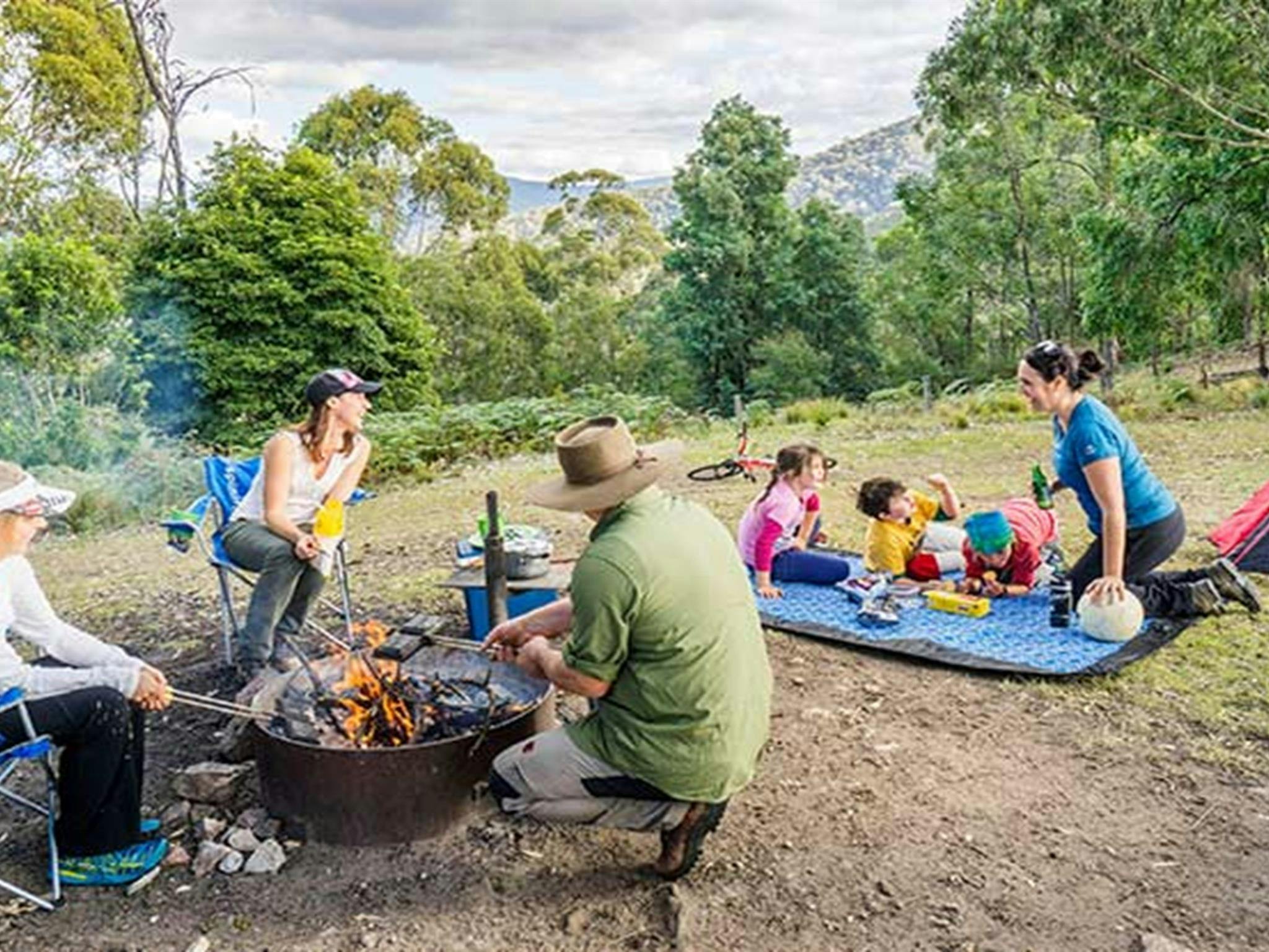 Kinder und Erwachsene versammeln sich an einem Lagerfeuer auf dem Campingplatz Dunphys im Blue Mountains Nationalpark.