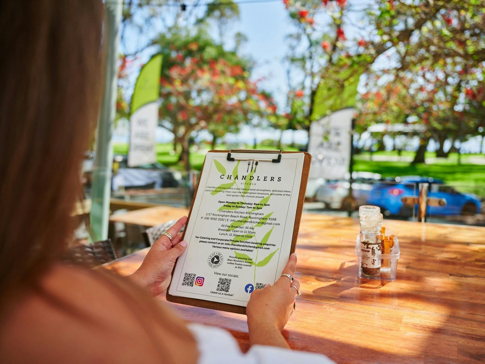 Woman looking at menu with a view of the beach in the background
