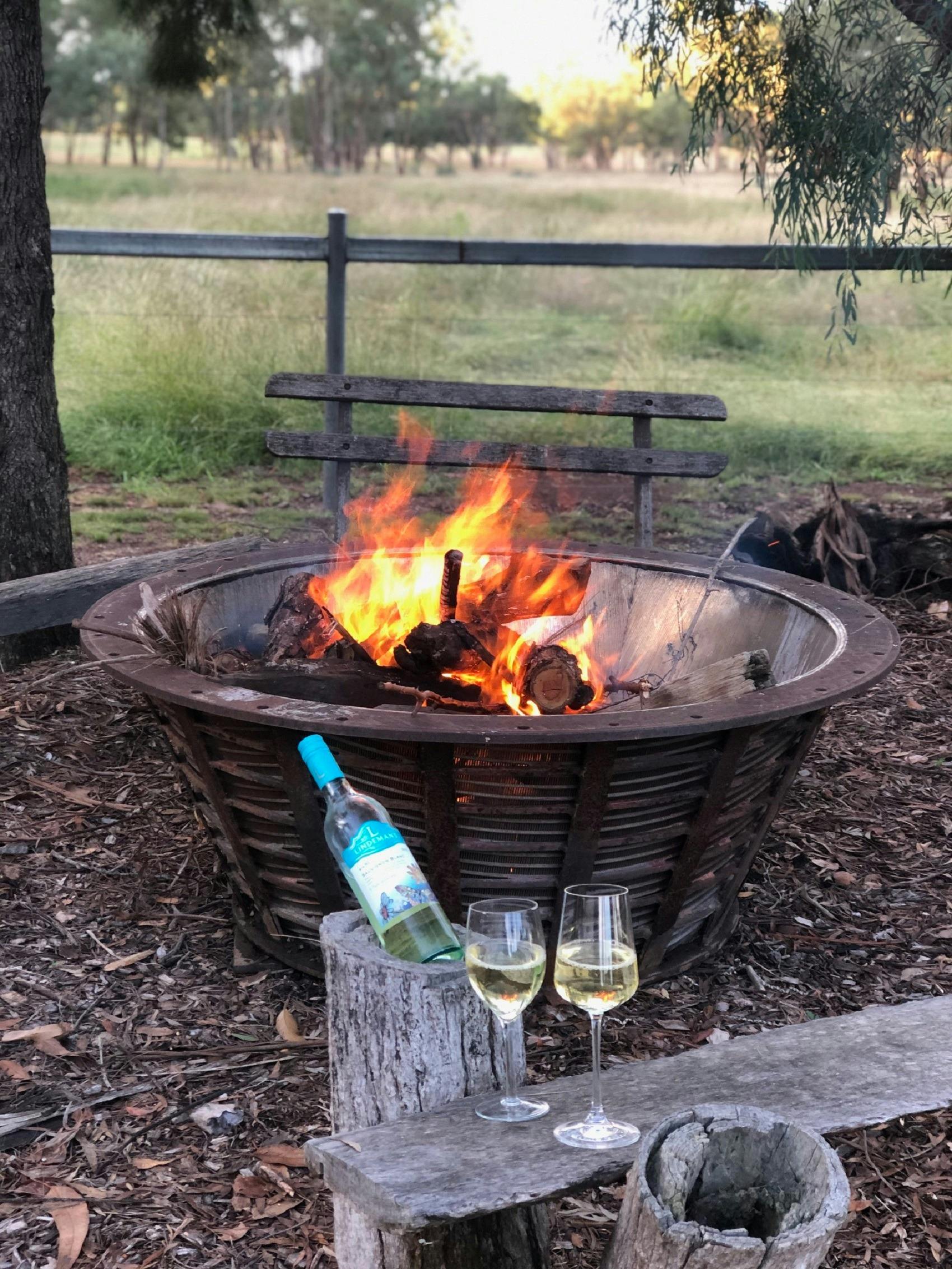 Fire Pit with fire burning and wine bottle with glasses in front