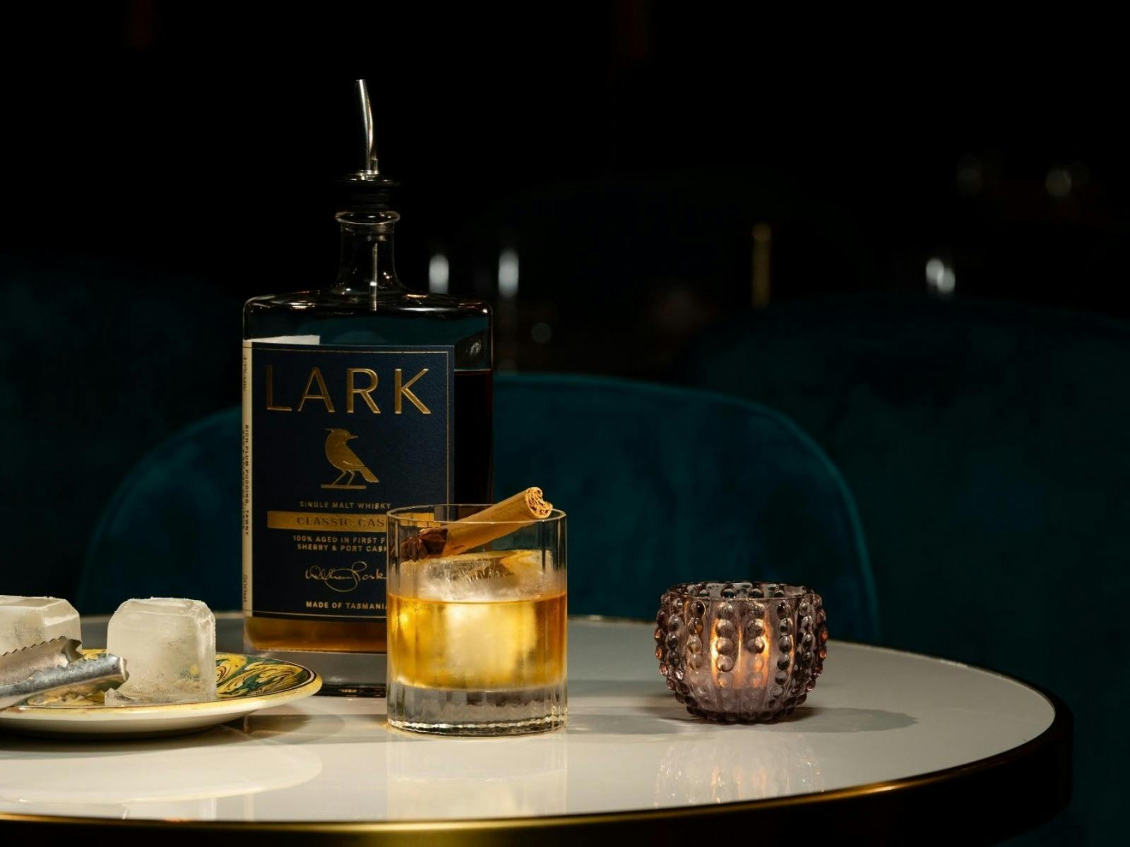 LARK Tasmanian single malt whisky served over ice beside the bottle in the elegant dining setting of