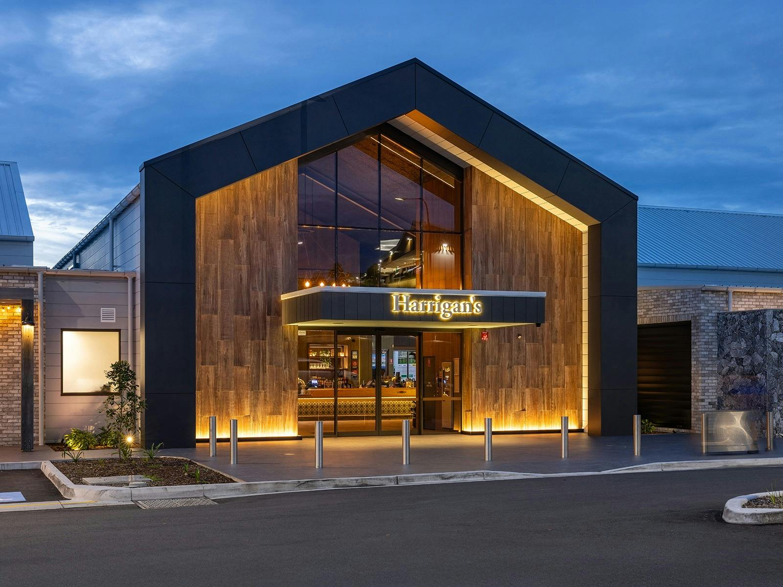 Exterior of large building at dusk with signage lit up that says Harrigan's