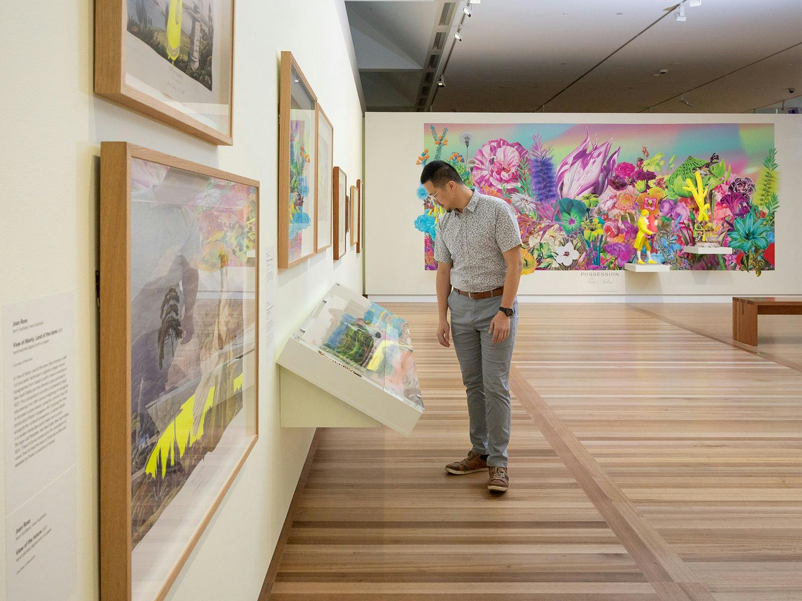 A man looking at a showcase inside the Joan Ross exhibition