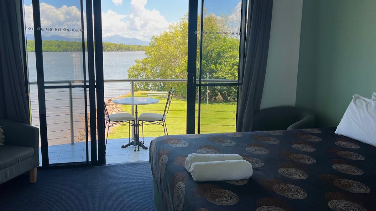 Grass and water views from balcony of upstairs room, with table and chairs