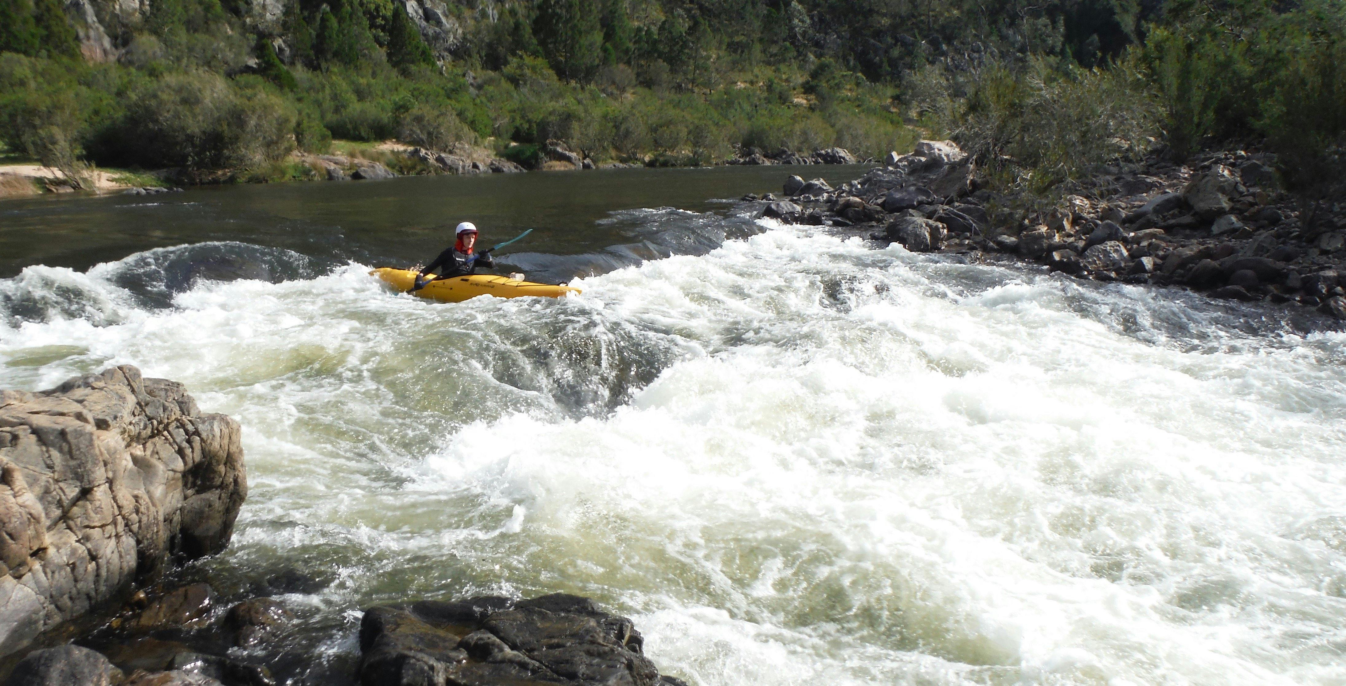 A boiling water rapid on the snowy river with a kayaker in a yellow about to enter the rapid