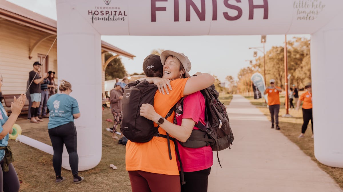 Trek the Trail Finish Line Photo - Two Attendees Embracing in Happiness