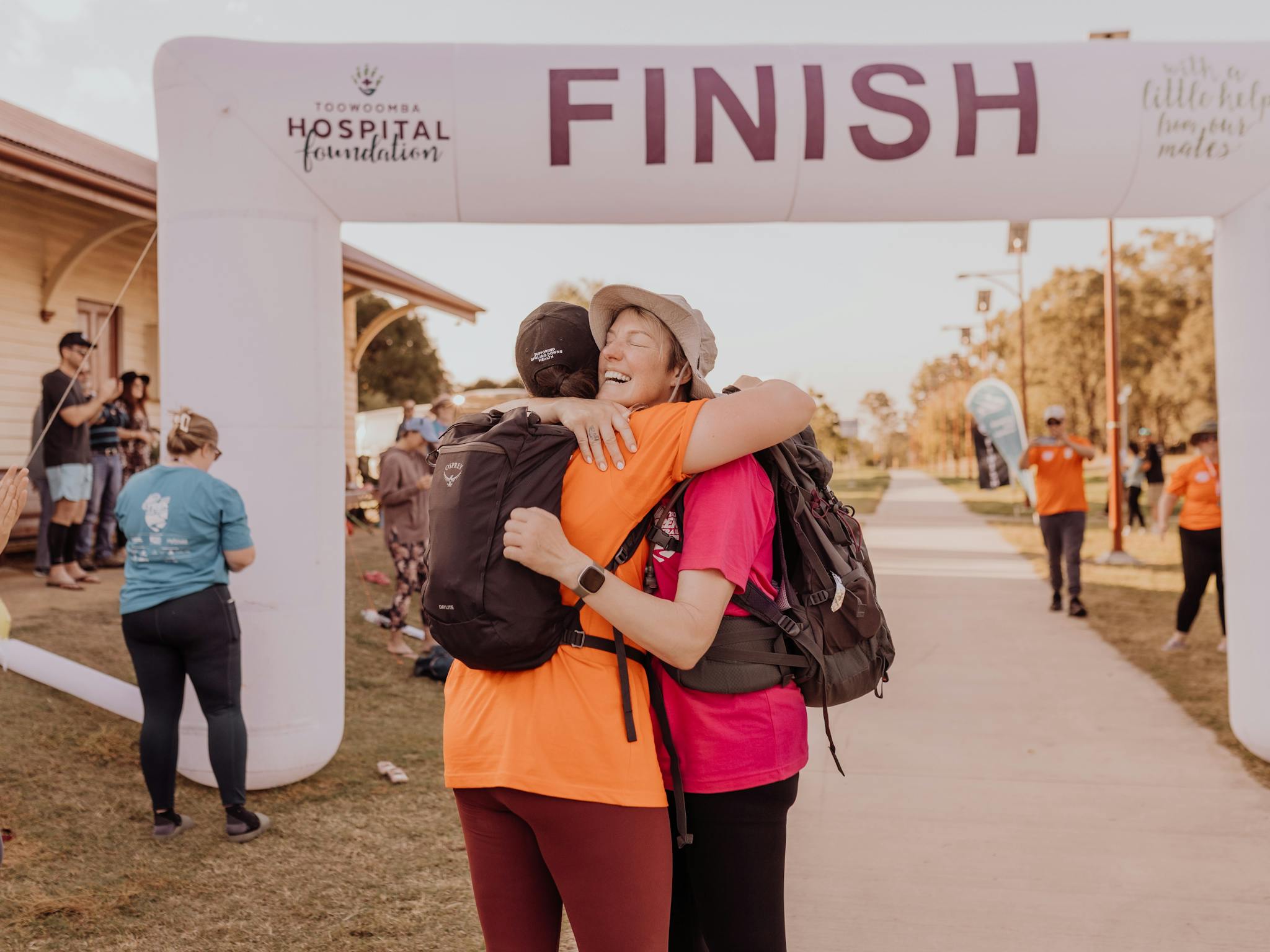 Trek the Trail Finish Line Photo - Two Attendees Embracing in Happiness Trek the Trail Finish Line Photo - Two Attendees Embracing in Happiness