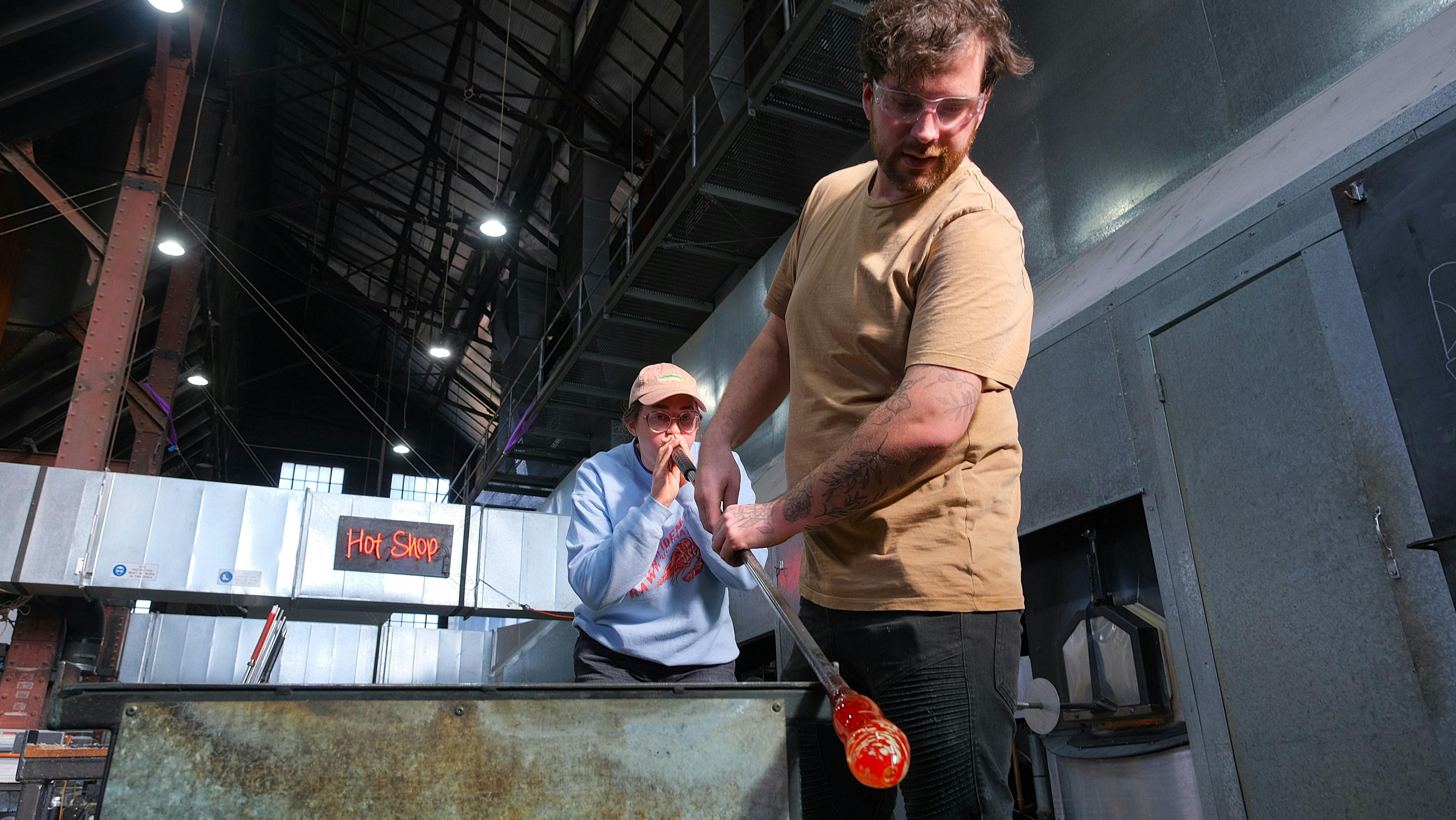 Participant and artist blowing glass